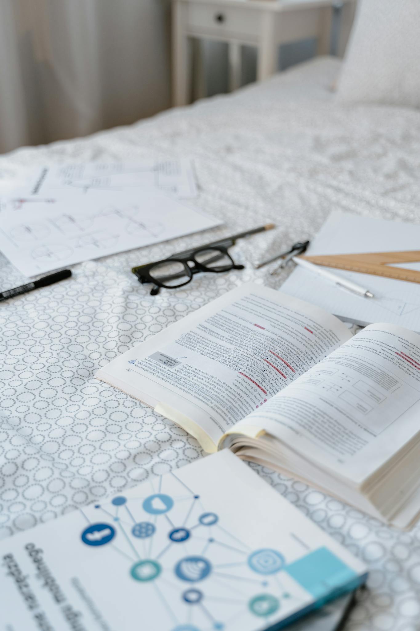Books, glasses, and study materials arranged on a bed, ideal for learning themes.